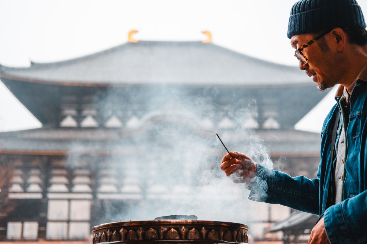 Man holding a smoking incense stick inside a temple