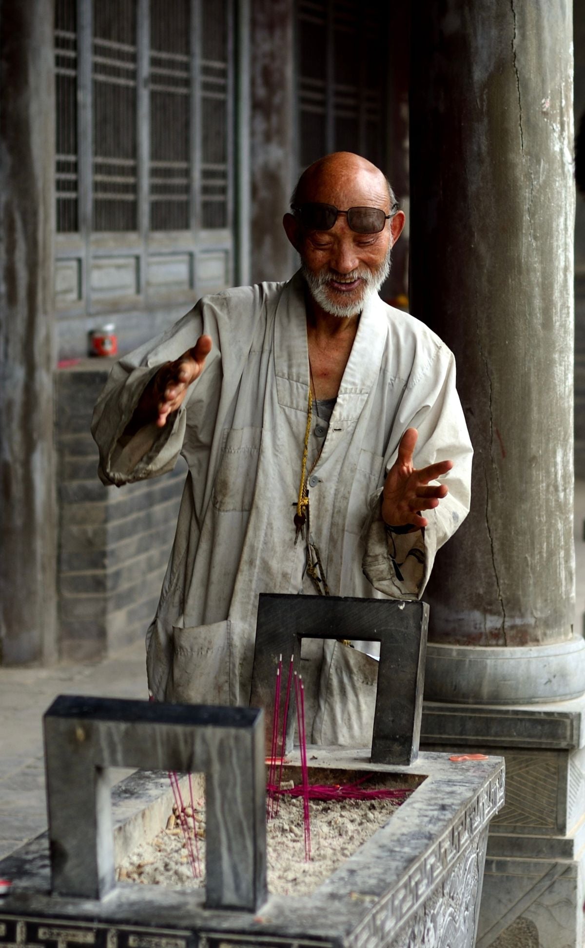 Elderly man lighting incense sticks in a traditional temple