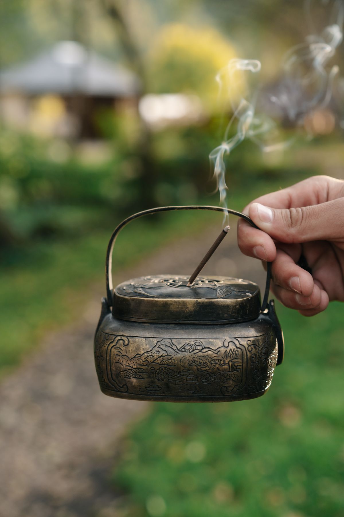 Hand holding a lit incense stick in a holder